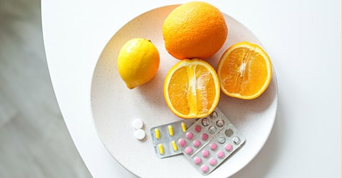 Oranges on a plate with white yellow and pink pills